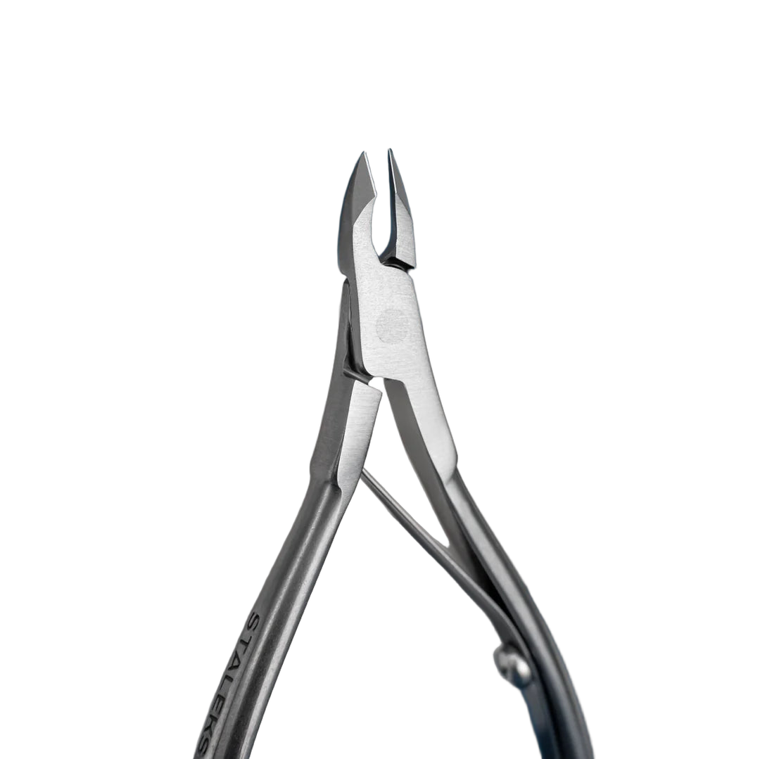 Close-up of the Staleks Classic 12 cuticle nipper 5mm half jaw against a dark blue background.