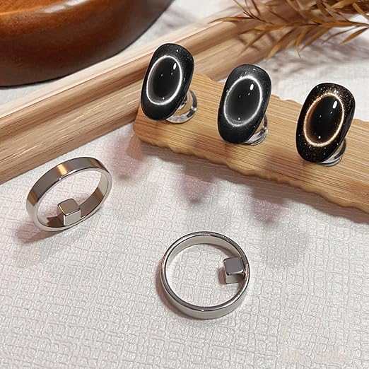 Set of silver rings with black stone accents on a wooden and fabric background