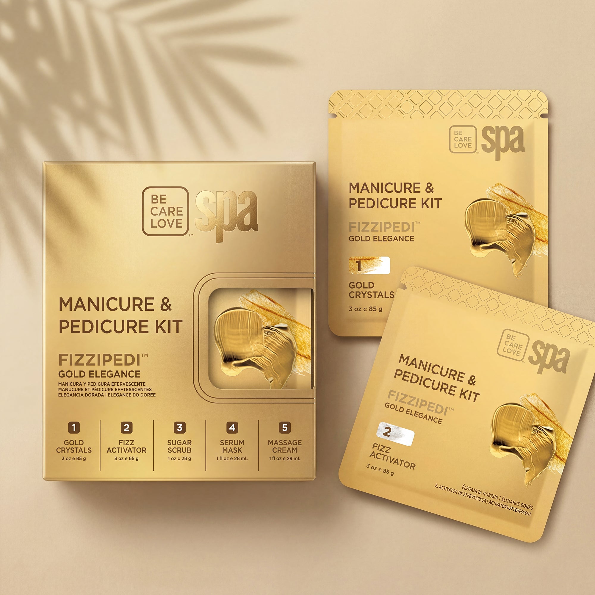 Be Care Love Spa Fizzipedi Gold Elegance Manicure & Pedicure Kit, showing the main gold box and two individual gold packet sachets on a beige background with soft leaf shadows.