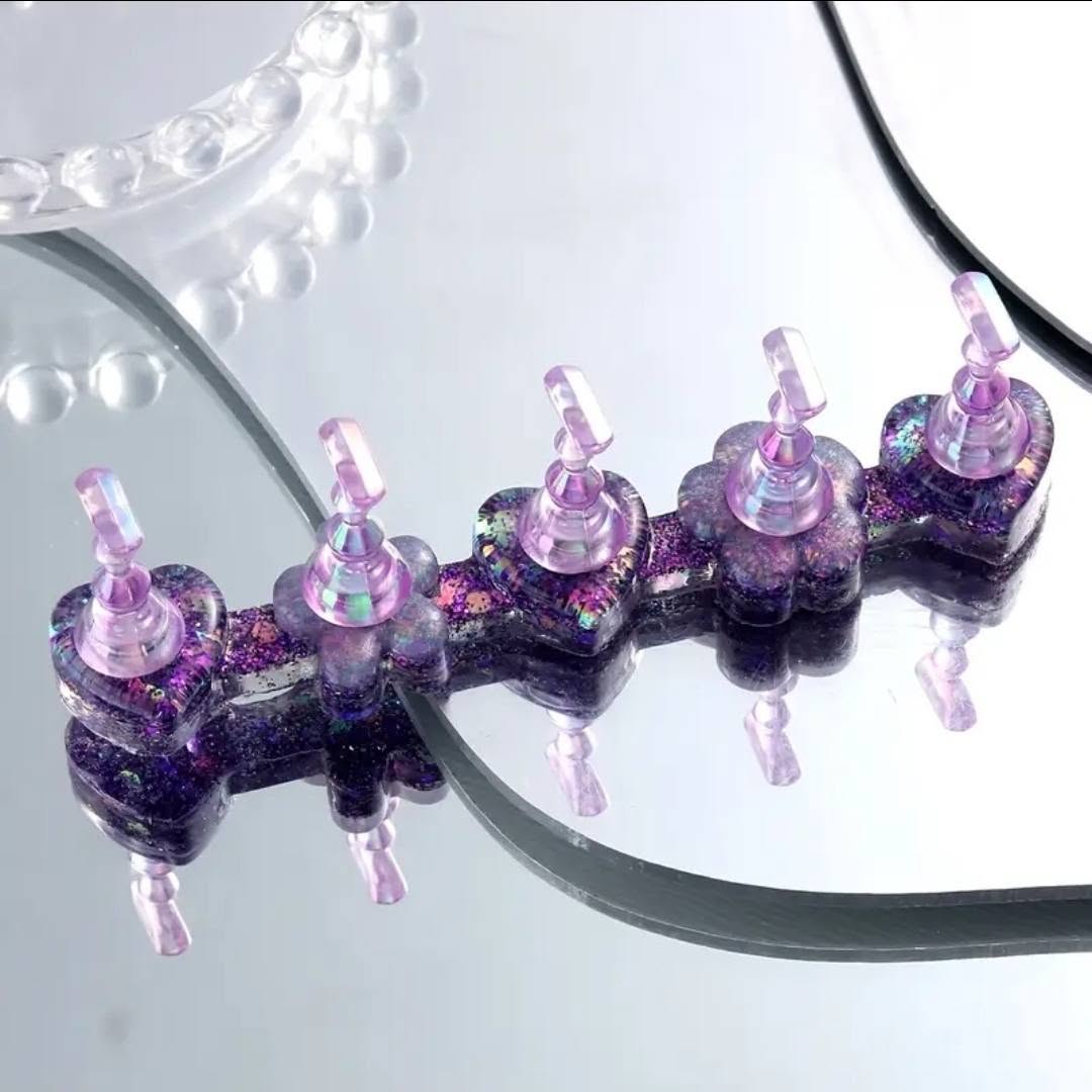Five Coconoir Beauty Aurora Purple nail tip holders with iridescent glitter bases on a mirrored surface