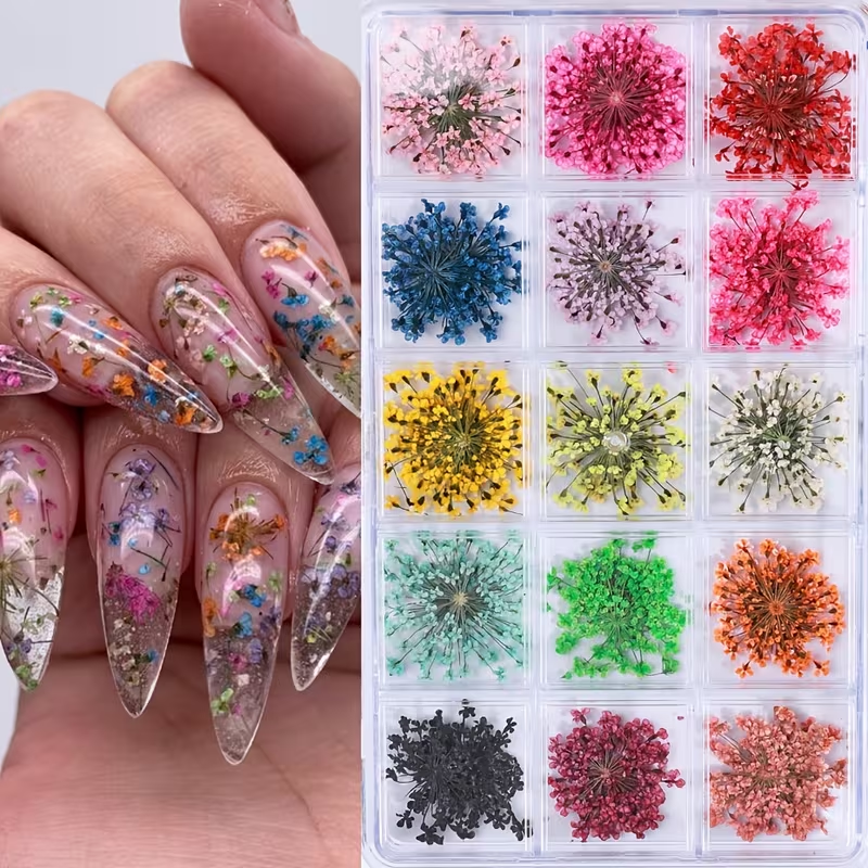 Nail art display with colorful dried flower decorations and a hand with decorated nails.