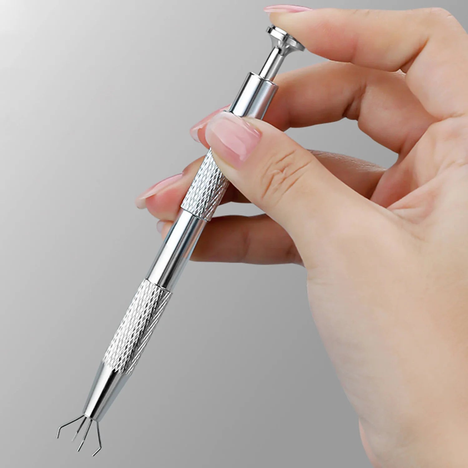 Hand holding a silver tool against a gray background