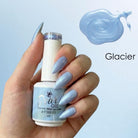 A hand holding a bottle of nail gel polish with a light icy blue shade, shown next to a matching nail swatch and the text 'Glacier'.