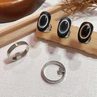 Set of silver rings with black stone accents on a wooden and fabric background