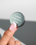 Control Ultra White jar lid held above a pale pink French nail