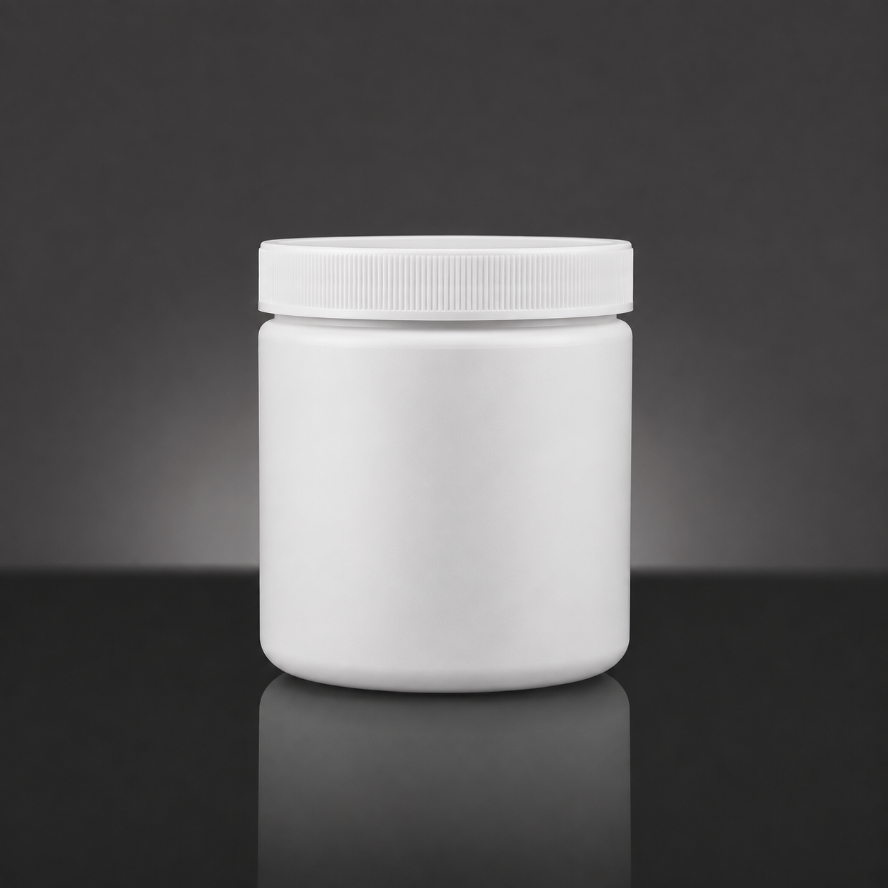 A blank white plastic jar with a ribbed screw-on lid, centered on a reflective dark gray surface against a dark gray gradient background.