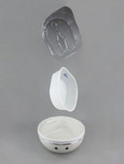 A white ceramic bowl with a small black logo, shown with its lid and a matching white scoop floating above it against a neutral gray background.