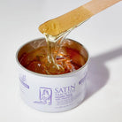 Can of Satin Smooth Honey Wax with a wooden applicator dripping wax onto a white background