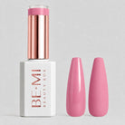 A bottle of BE-MI Beauty Box nail polish in a soft pink shade, shown next to two almond-shaped nail tips coated in the same pink polish, on a light gray background.